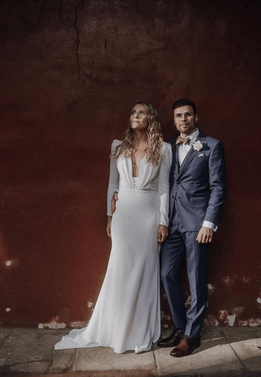 Brautpaar am Hochzeitstag vor einer roten Wand